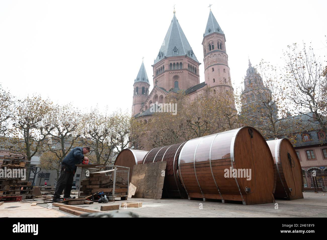 Magonza, Germania. 11 Nov 2021. Un operaio sega un piatto di fronte alla cattedrale di Mainz, che serve come base per botti a forma di botte. I visitatori del mercato di Natale possono quindi sedersi in loro. (A dpa: '2G, 3G o maschere obbligatorie? Cosa è previsto per i mercati di Natale') Credit: Sebastian Gollnow/dpa/Alamy Live News Foto Stock