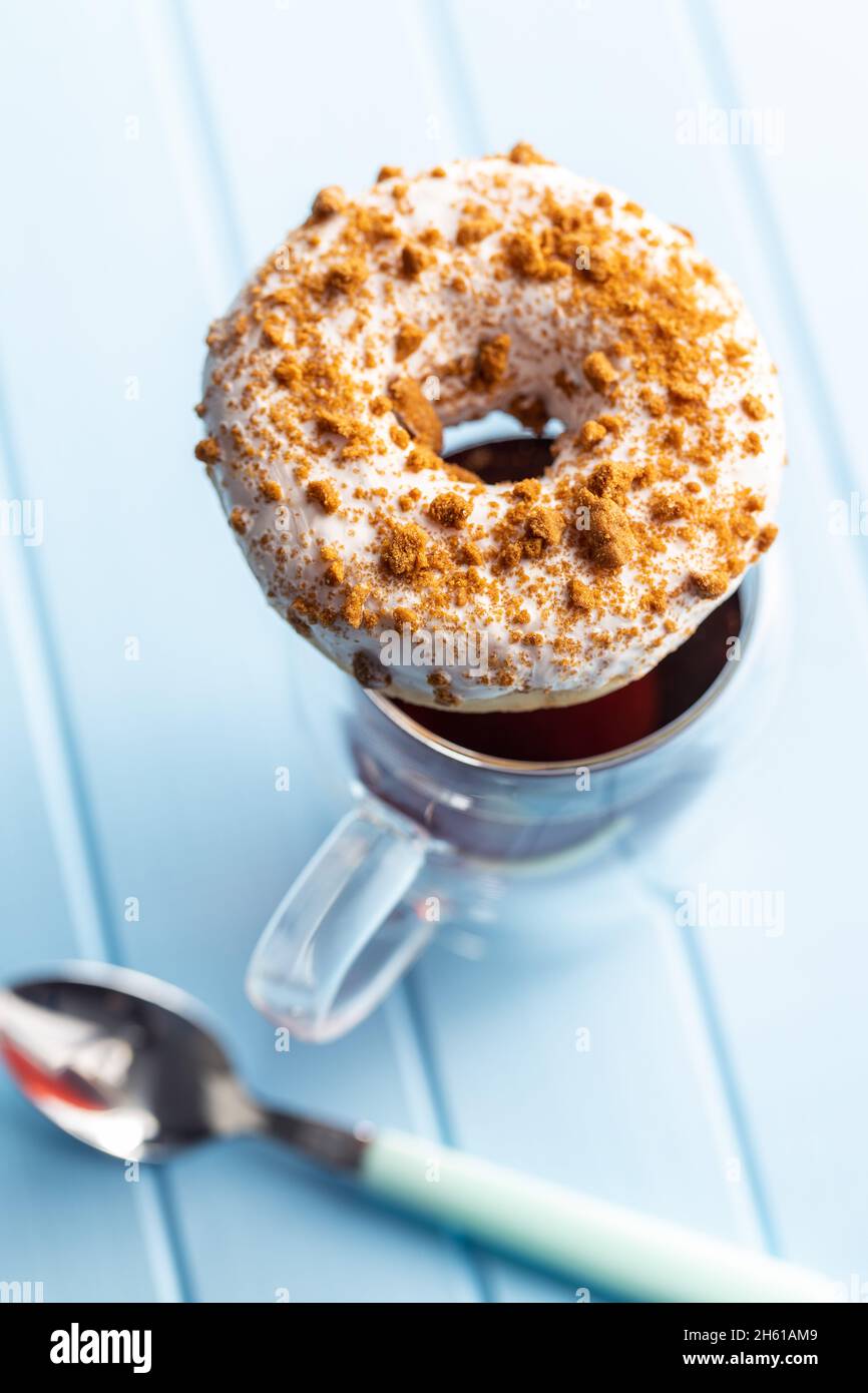 Ciambella glassata dolce con spolverini e tè sul tavolo da cucina blu. Foto Stock