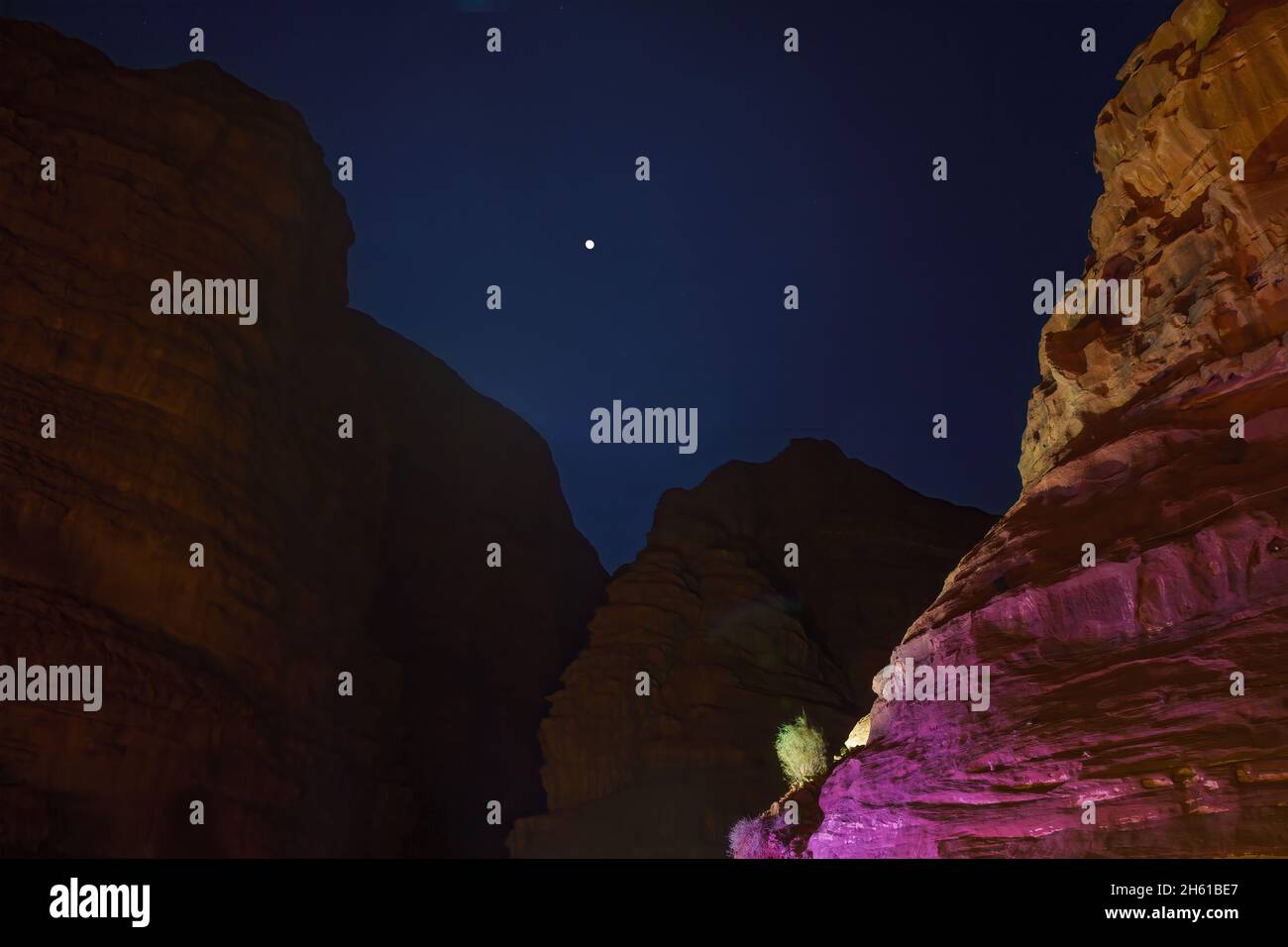 Vista notturna delle scogliere rocciose e della luna, a Wadi Rum, parco del deserto nel sud della Giordania Foto Stock