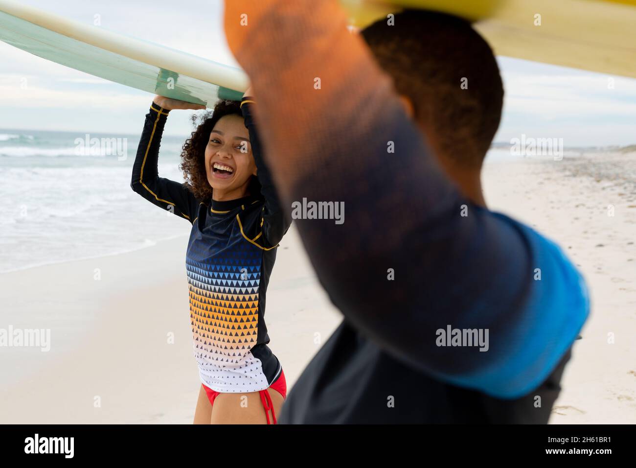 Felici amici donne multirazziali che trasportano tavole da surf sulla testa in spiaggia durante il fine settimana Foto Stock