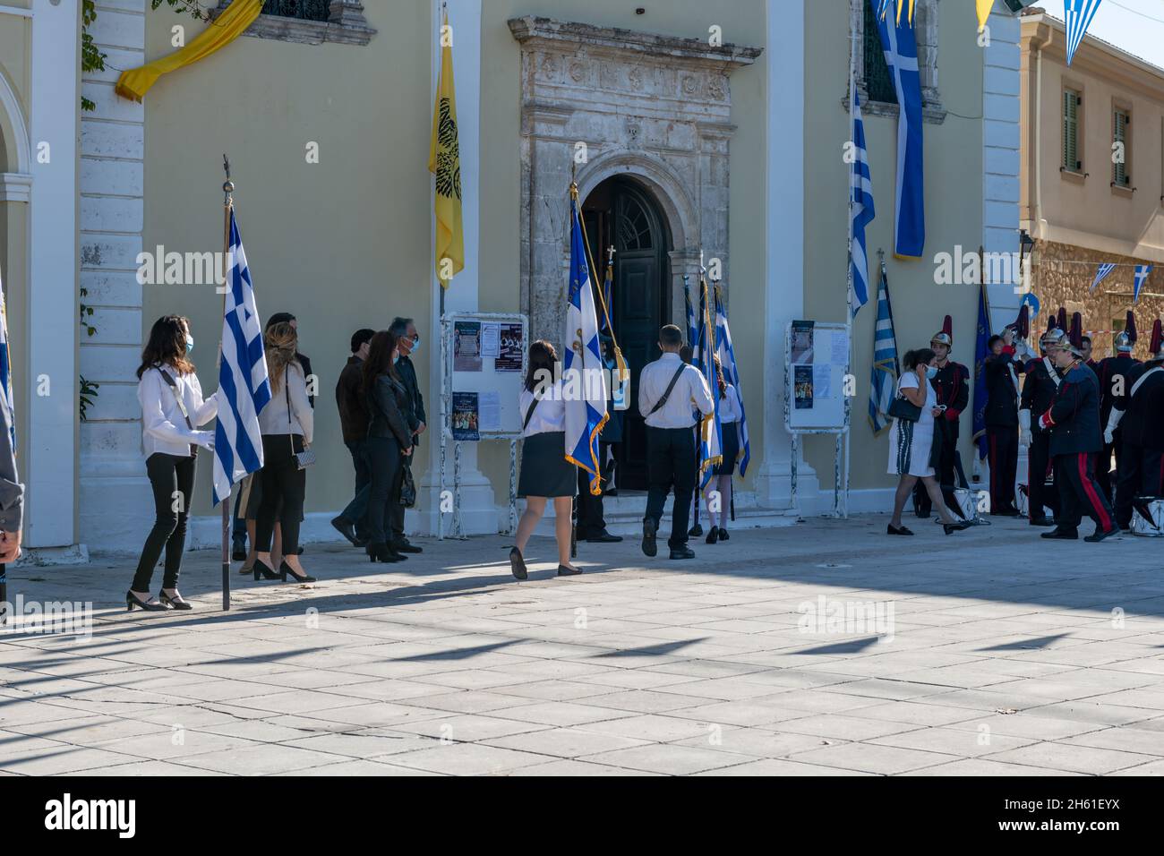 Lefkada. Grecia. 10.28.2021. Giovani che detengono la bandiera nazionale che entrano in chiesa per il servizio in occasione della celebrazione del giorno di Oxi. Foto Stock