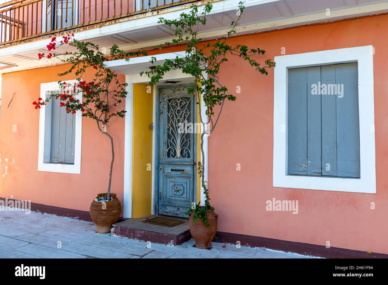 Una colorata e bella facciata greca casa con una porta tradizionale, finestre e decorate con piante fiorite. Foto Stock