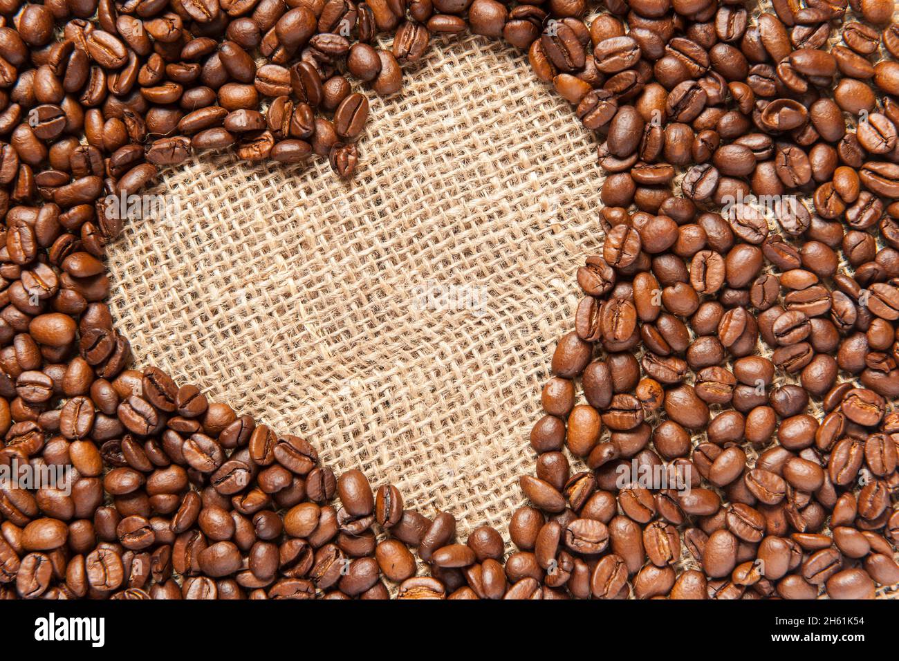 Vista formatabile di una struttura inclinata a forma di cuore realizzata con chicchi di caffè torrefatti su sackcount. Foto Stock