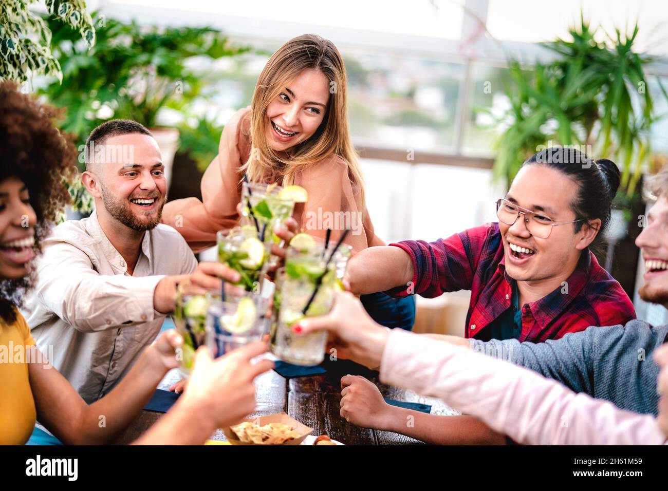 Giovani amici che tostano bevande mojito al cocktail bar sul tetto - Party Time Concept con persone multiculturali che si divertono a bere durante l'happy hour Foto Stock