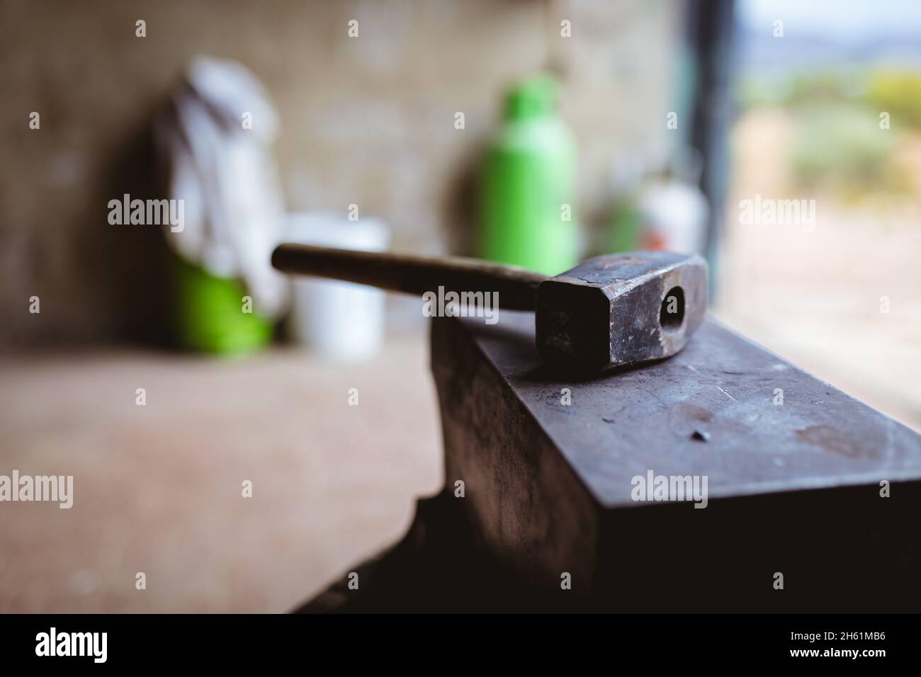 Primo piano del martello con manico in legno sull'incudine nell'industria Foto Stock