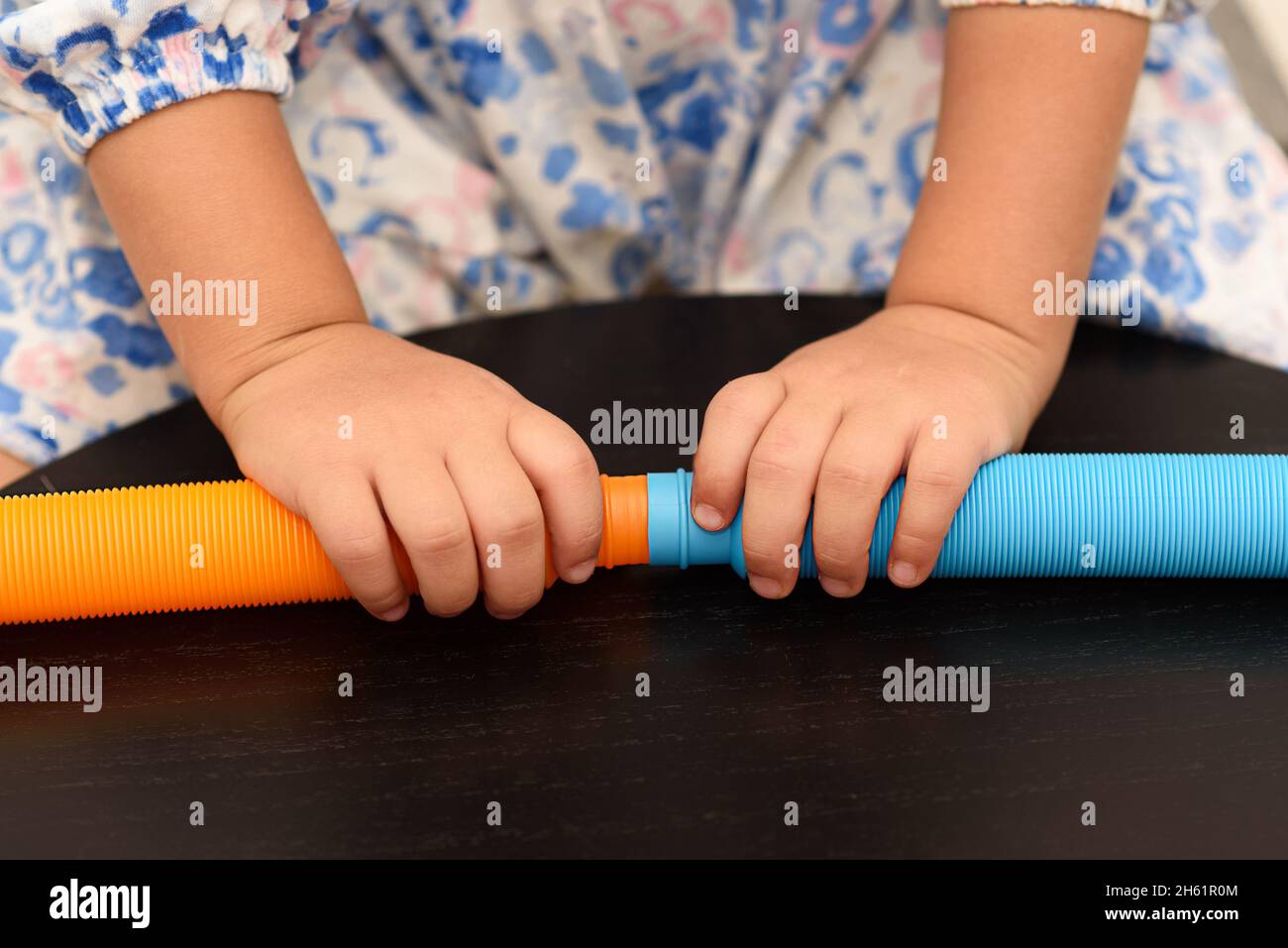 Fidget Pop tubi sensoriali giocattolo. Cute bambino senza volto giocando con il Pop tubi Fidget. Foto Stock