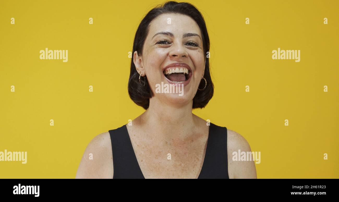 Bella donna di mezza età con bel sorriso sul muro giallo. Donna piuttosto anziana, fiducia riuscita. Foto Stock