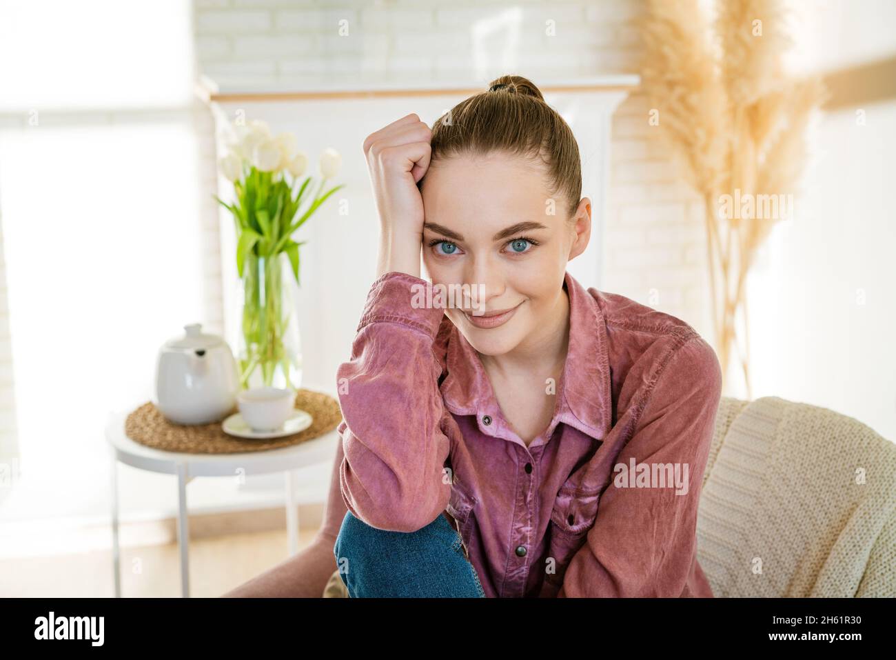 Felice calma giovane donna rilassarsi su comoda poltrona in soggiorno, sorridente ragazza millenaria divertirsi rilassarsi in poltrona a casa senza stress godere sano week-end Foto Stock