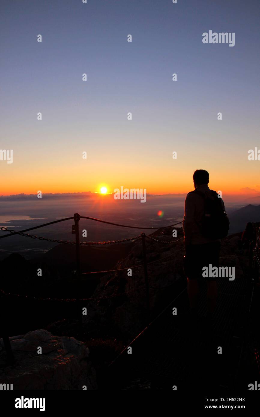 giovane uomo, vista dalla cima del kampenwand (1669 m) nel chiemgau, escursione, alba, vista sul mare delle nuvole, alpi chiemgau, vicino aschau, alta baviera, baviera, germania meridionale, germania Foto Stock