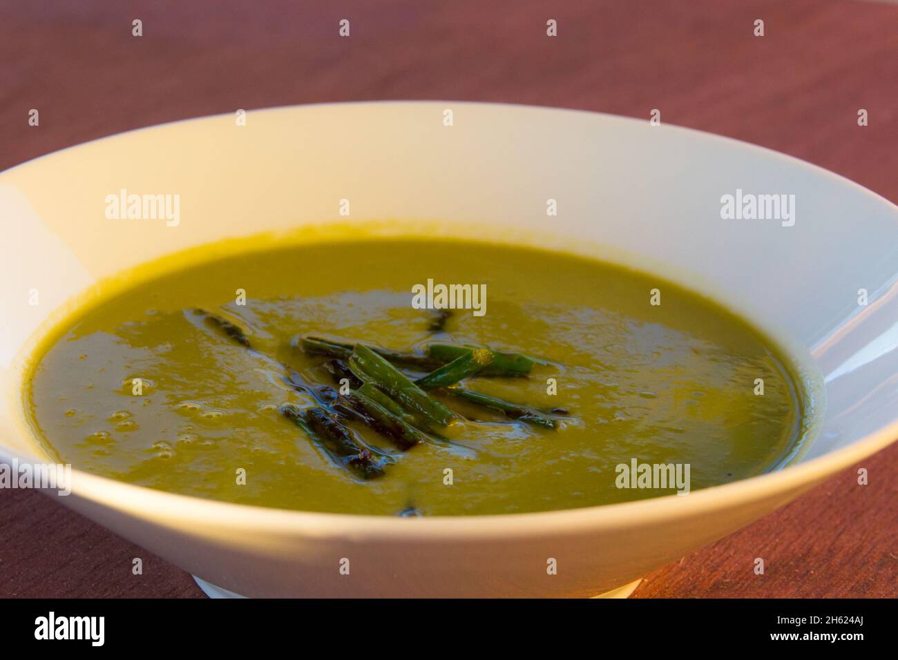 Zuppa di asparagi verde cremoso su ciotola bianca e fondo tavola in legno Foto Stock