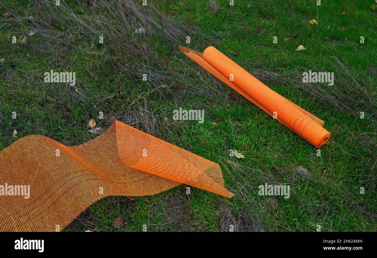 Rete intonacata in fibra arancione brillante in rotolo e arrotolata sull'erba. Foto Stock