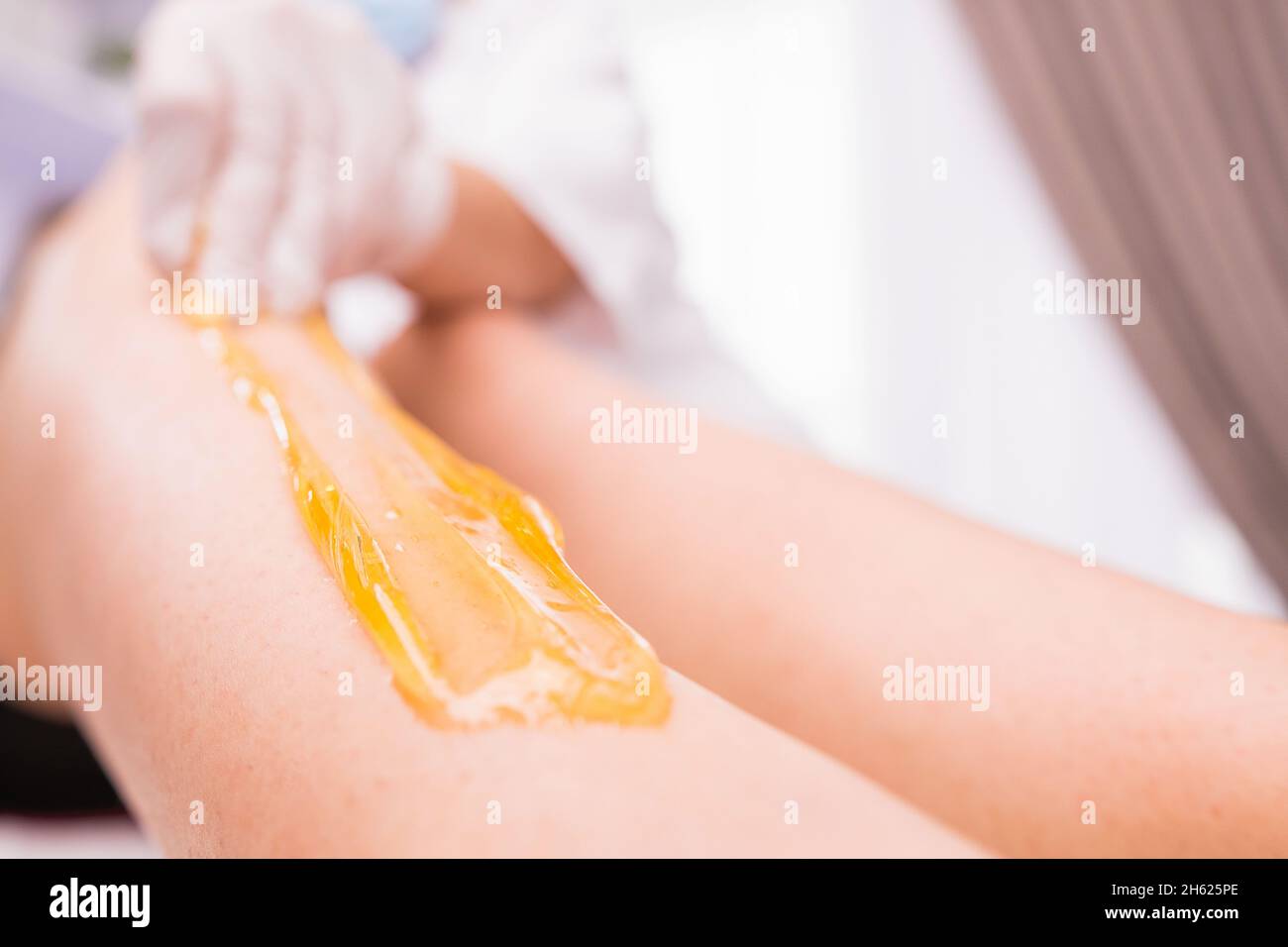 Foto ritagliata della procedura di epilazione con ceretta per la rimozione dei capelli con pasta zuccherata nel salone di bellezza, centro termale bellezza e cura del corpo concetto. Foto Stock