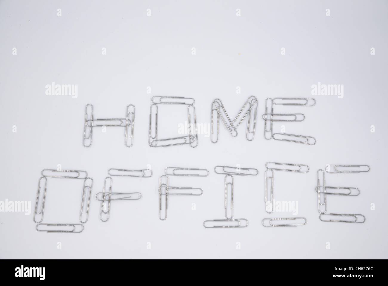 'Home Office' scritto con graffette metalliche sullo sfondo del white paper. Disposizione piatta. Rimani a casa. Lavoro a distanza. Istruzione remota. Quarantena. Autoisola Foto Stock