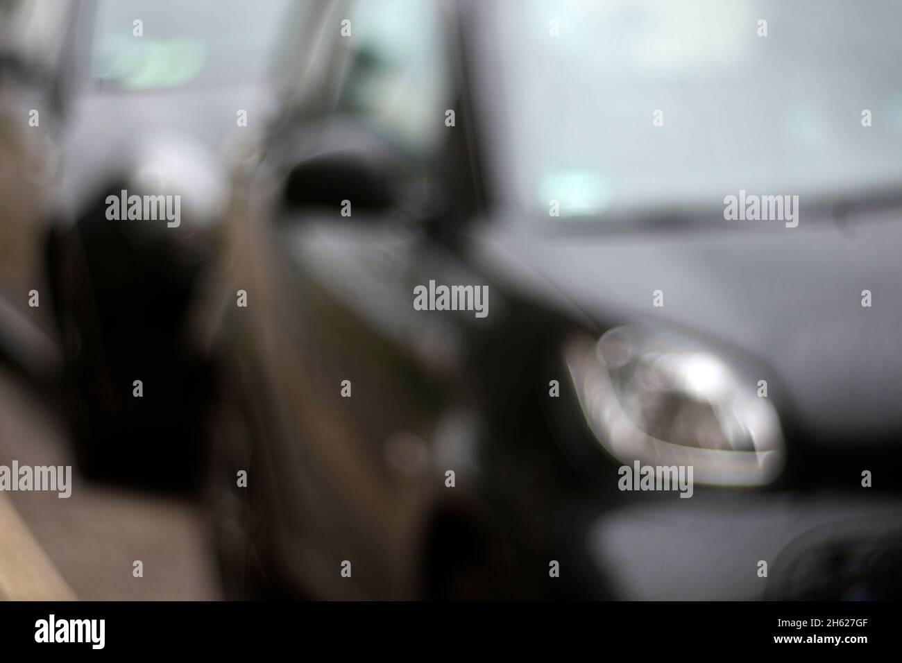 faro destro di un'auto nera parcheggiata, sfocatura astratta Foto Stock