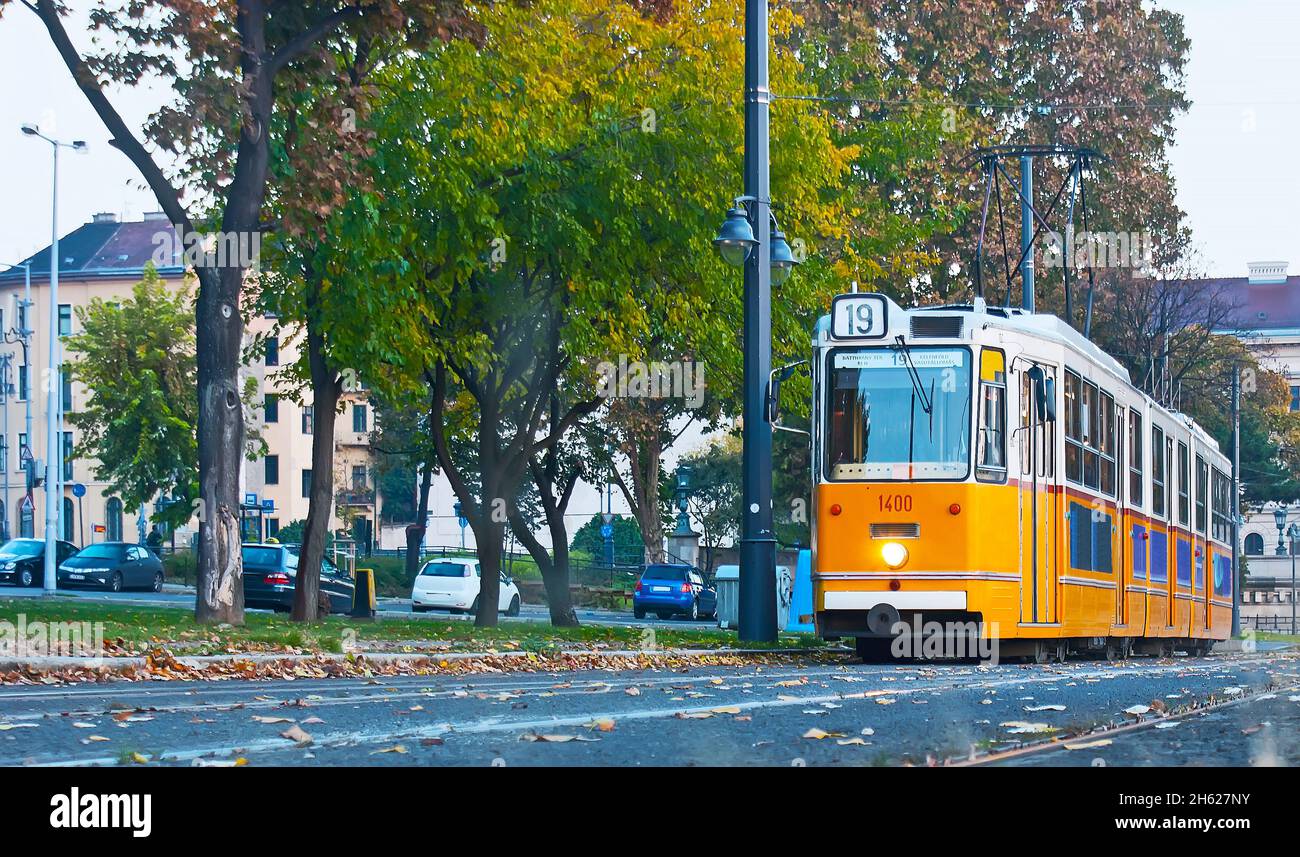 Il tram d'epoca percorre il quartiere Varkert Quay di Buda lungo il piccolo parco verde di Budapest, Ungheria Foto Stock