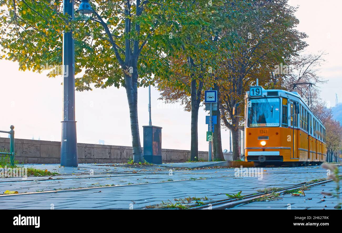 Il tram retrò yallow si trova a Varkert Quay, con vista ad angolo basso, Budapest, Ungheria Foto Stock