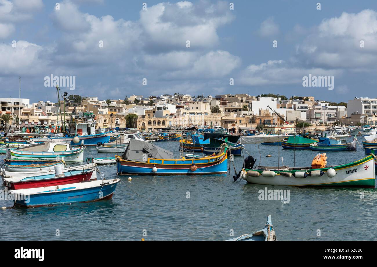 Vista pittoresca del porto di Marsaxlokk con una tradizionale barca da pesca Luzzu più molte altre barche da pesca, villaggio di Marsaxlokk, Malta Foto Stock