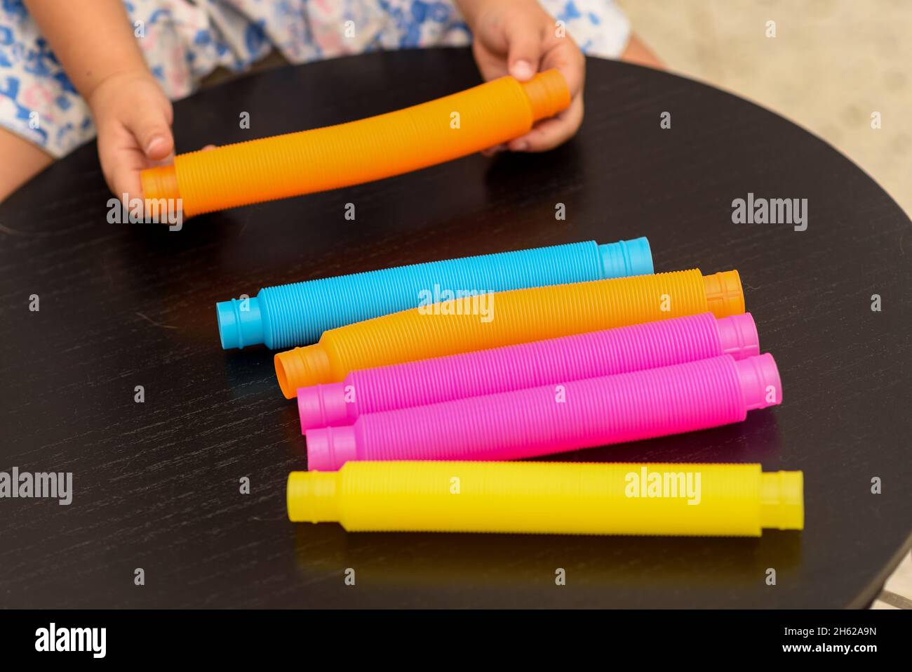 Fidget Pop tubi sensoriali giocattolo. Cute bambino senza volto giocando con il Pop tubi Fidget. Messa a fuoco selettiva. Foto Stock