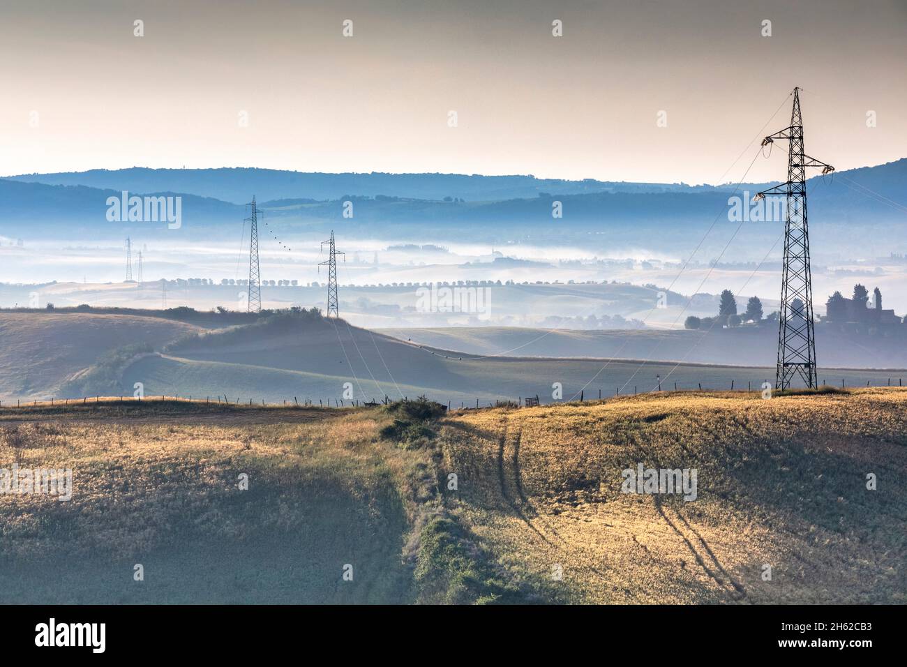 colline toscane attraversate da una linea elettrica ad alta tensione,asciano,provincia di siena,toscana,italia Foto Stock