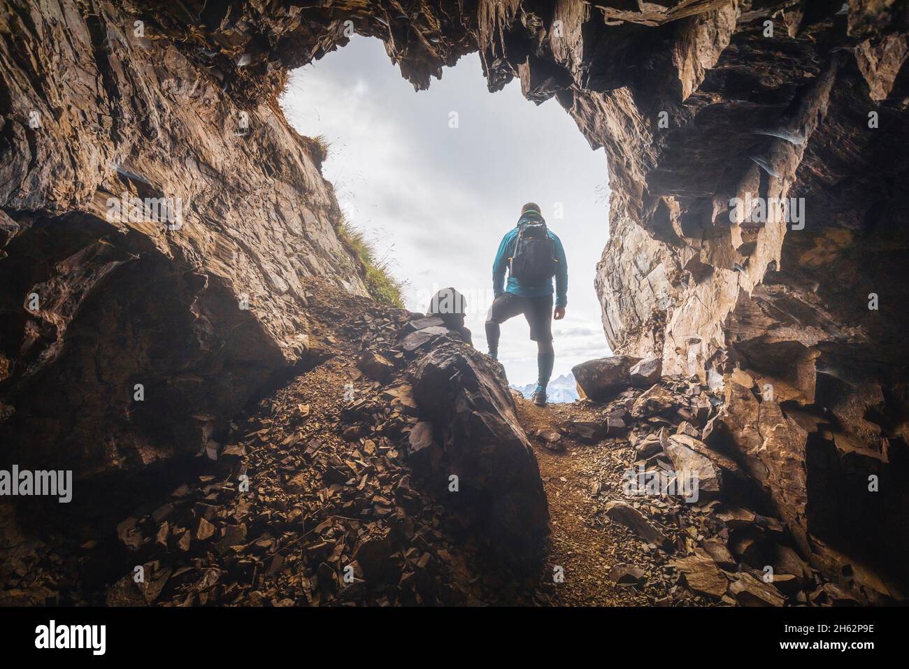 uomo solitario,35 - 40 anni,escursionista in controluce all'ingresso di una grotta in montagna,col di lana,dolomiti,livinallongo del col di lana,belluno,veneto,italia Foto Stock