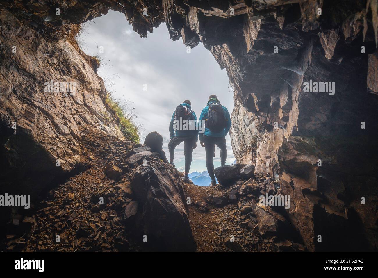 due escursionisti in controluce all'ingresso di una grotta in montagna,col di lana,dolomiti,livinallongo del col di lana,belluno,veneto,italia Foto Stock