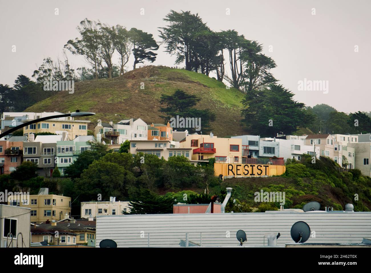 Inner Sunset District, vista dal Golden Gate Park, case pastello su una collina con alberi di eucalipto e un segno 'resist'. San Francisco, California. Foto Stock
