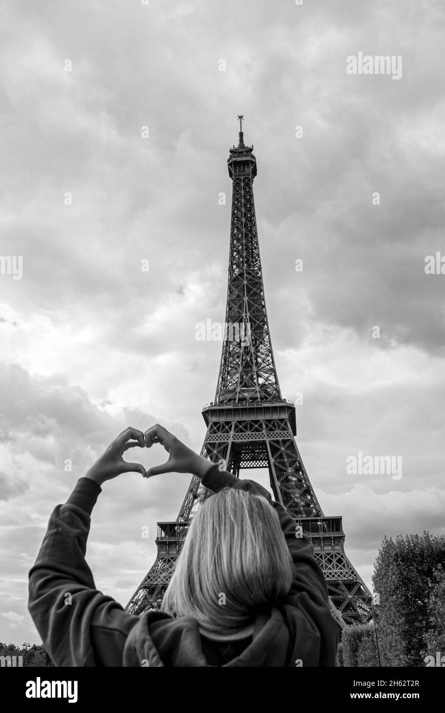 francia,parigi,ãžle-de-france,la giovane donna forma un cuore di fronte alla torre eiffel Foto Stock