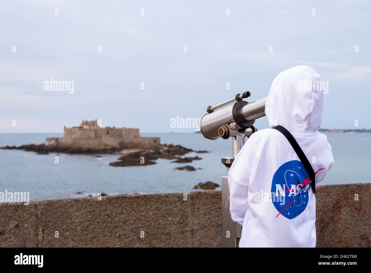 francia,bretagna,ille et vilaine,saint malo,ragazzo guarda attraverso un telescopio fino all'isola marea di petit-bé con il forte nazionale, costa atlantica Foto Stock