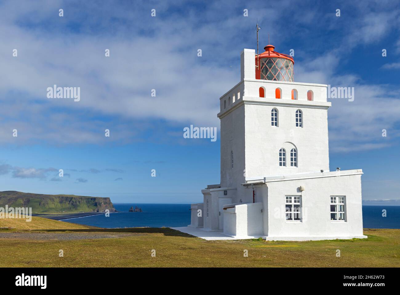 faro a capo dyrholaey sulla costa meridionale dell'islanda, sullo sfondo la cresta reynisfjall e la roccia pinnacles reynisdrangar, islanda Foto Stock
