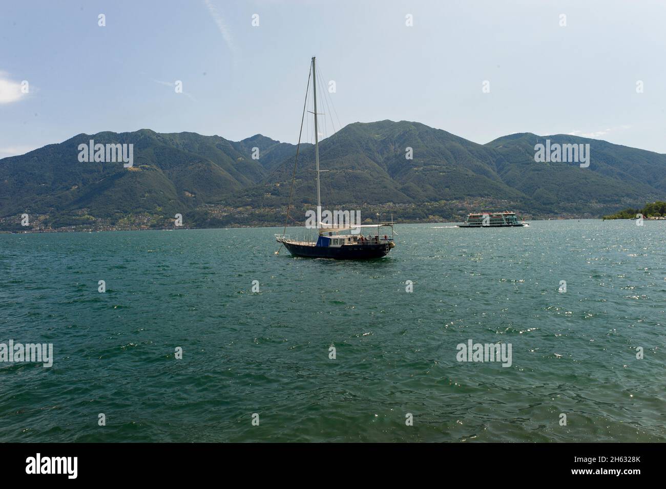 una barca sull'acqua con alcune montagne sul retro - lago di maggiore Foto Stock