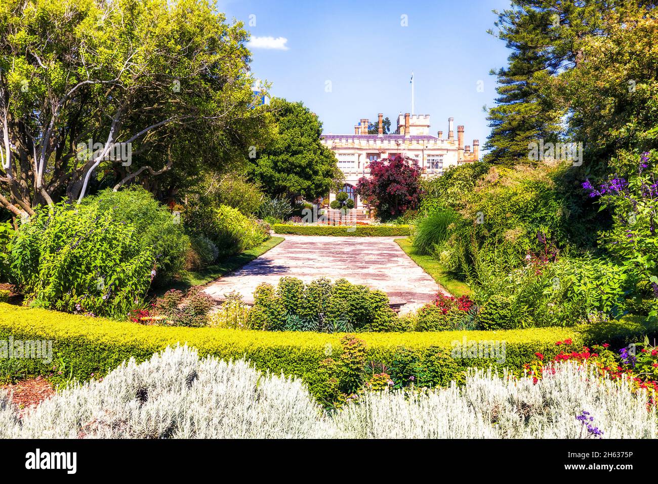 Giardino coltivato fiorito nel parco pubblico della città di Sydney intorno alla storica casa coloniale in sole estate tempo e cielo blu. Foto Stock