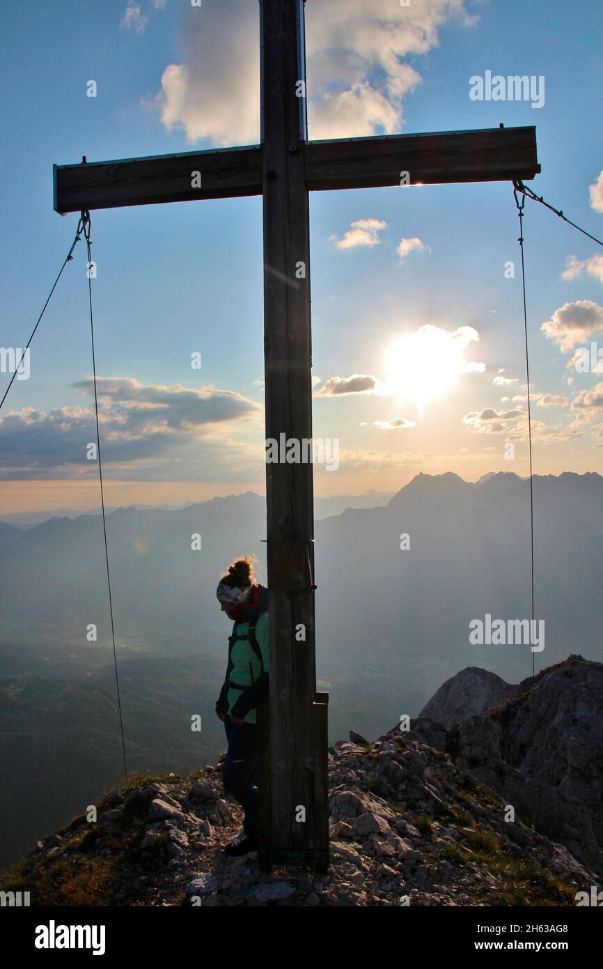 giovane donna, croce di montagna all'alba, escursione, obere wettersteinspitze, 2.297m germania, baviera, alta baviera, werdenfelser terra, mittenwald, valle isar Foto Stock
