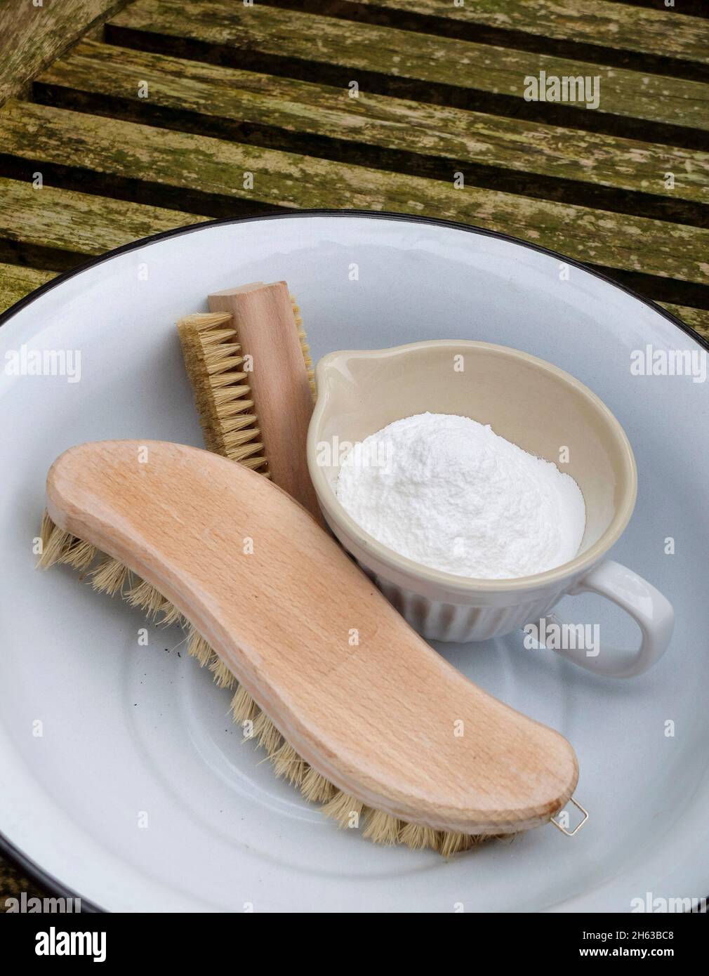 pulire i mobili da giardino dopo l'inverno; soda (bicarbonato di sodio), spazzola e ciotola Foto Stock