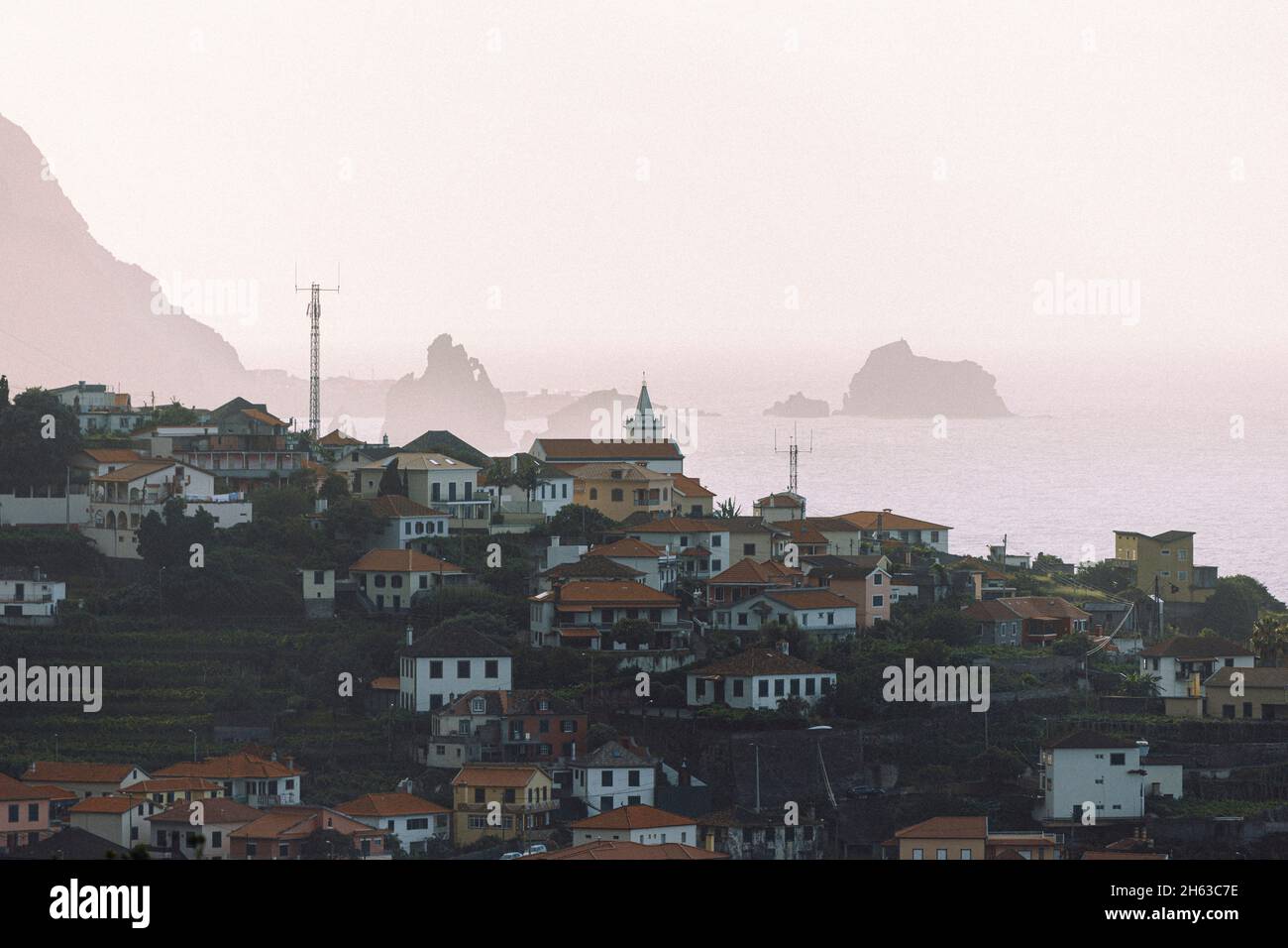 piccolo villaggio su un promontorio lungo la costa selvaggia dell'isola di madeira al tramonto, sullo sfondo ci sono formazioni rocciose nel mare. Foto Stock