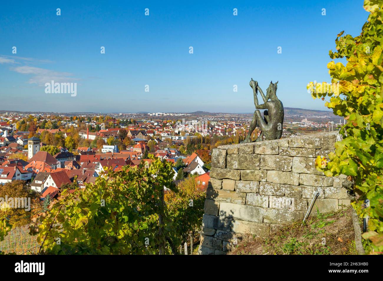 germania,baden-wuerttemberg,kernen im remstal,lo spirito del vino si trova sulla parete di pietra asciutta sul burgsteige a yburg con vista sul villaggio del vino di stetten, la "porta di accesso al remstal". l'artista dello spirito metallo-plastica, chiamato anche deifele o teufelchen, è karl ulrich nuss. Foto Stock