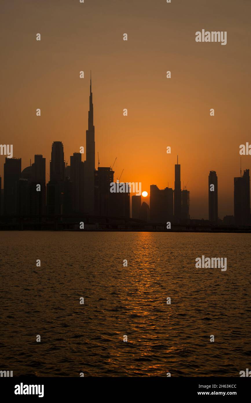 Silhouette Burj Khalifa e alti edifici al tramonto Dubai Canal UAE Foto Stock