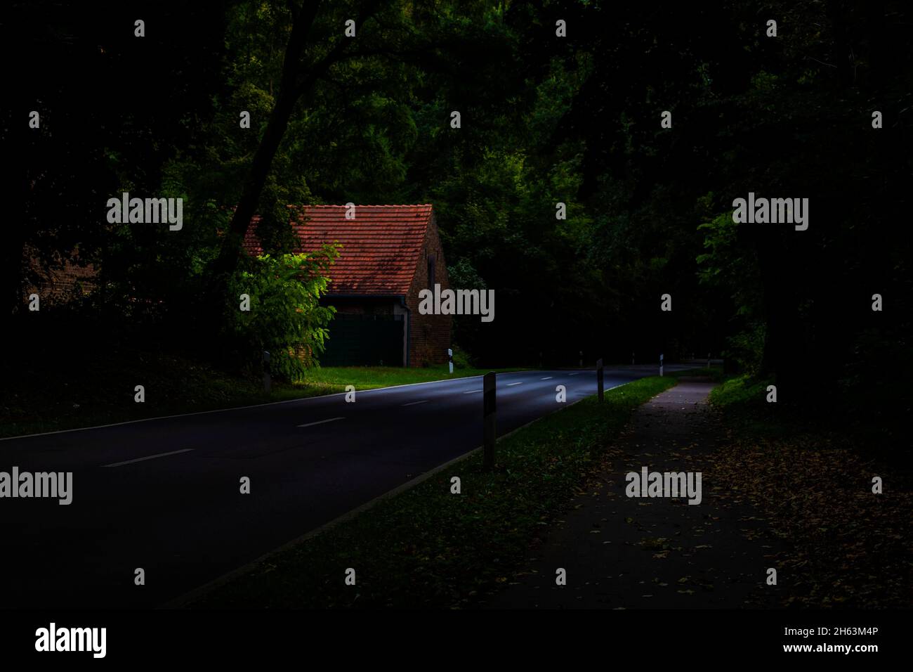 strade di campagna con un sacco di luce e ombra, fotografia a basso tasto, fienile contadino sulla strada Foto Stock