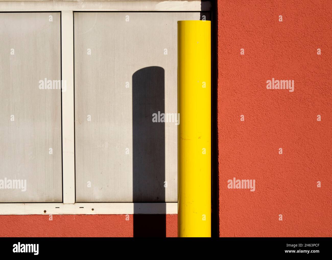 uno scooter giallo proietta un'ombra su un muro Foto Stock
