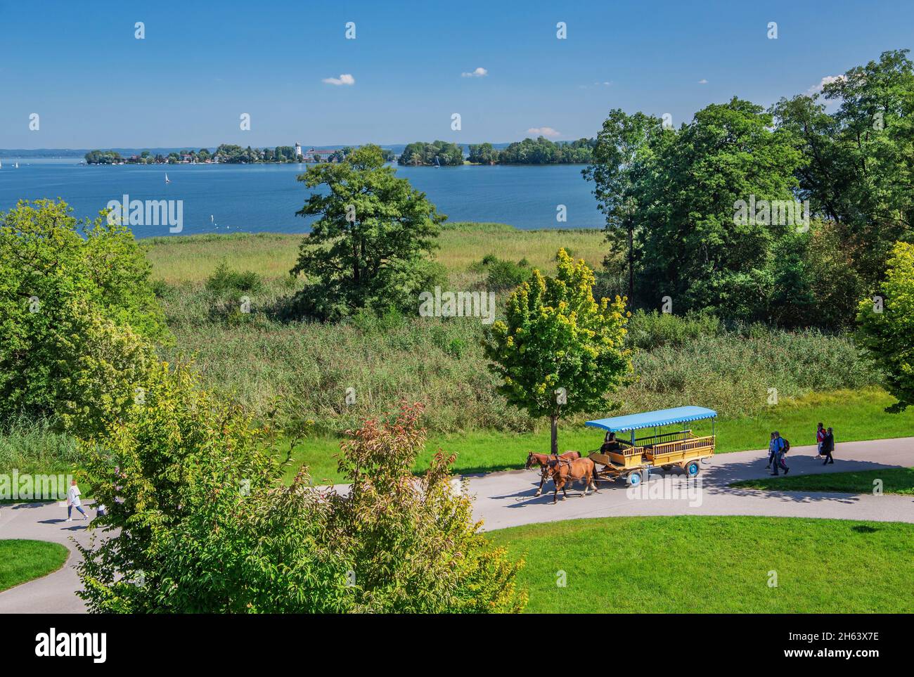 carrozza trainata da cavalli sull'isola con vista sul lago di fraueninsel, comune di chiemsee, herreninsel, chiemgau, alta baviera, baviera, germania Foto Stock