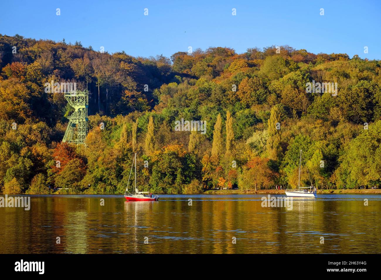 essen, renania settentrionale-vestfalia, germania - autunno dorato al lago Baldeney. barche a vela di fronte al telaio del trasportatore dell'ex collirio carl funke. La collirio carl funke era una miniera di carbone ad essen-Heisingen sulla riva settentrionale del lago Baldeney. Foto Stock