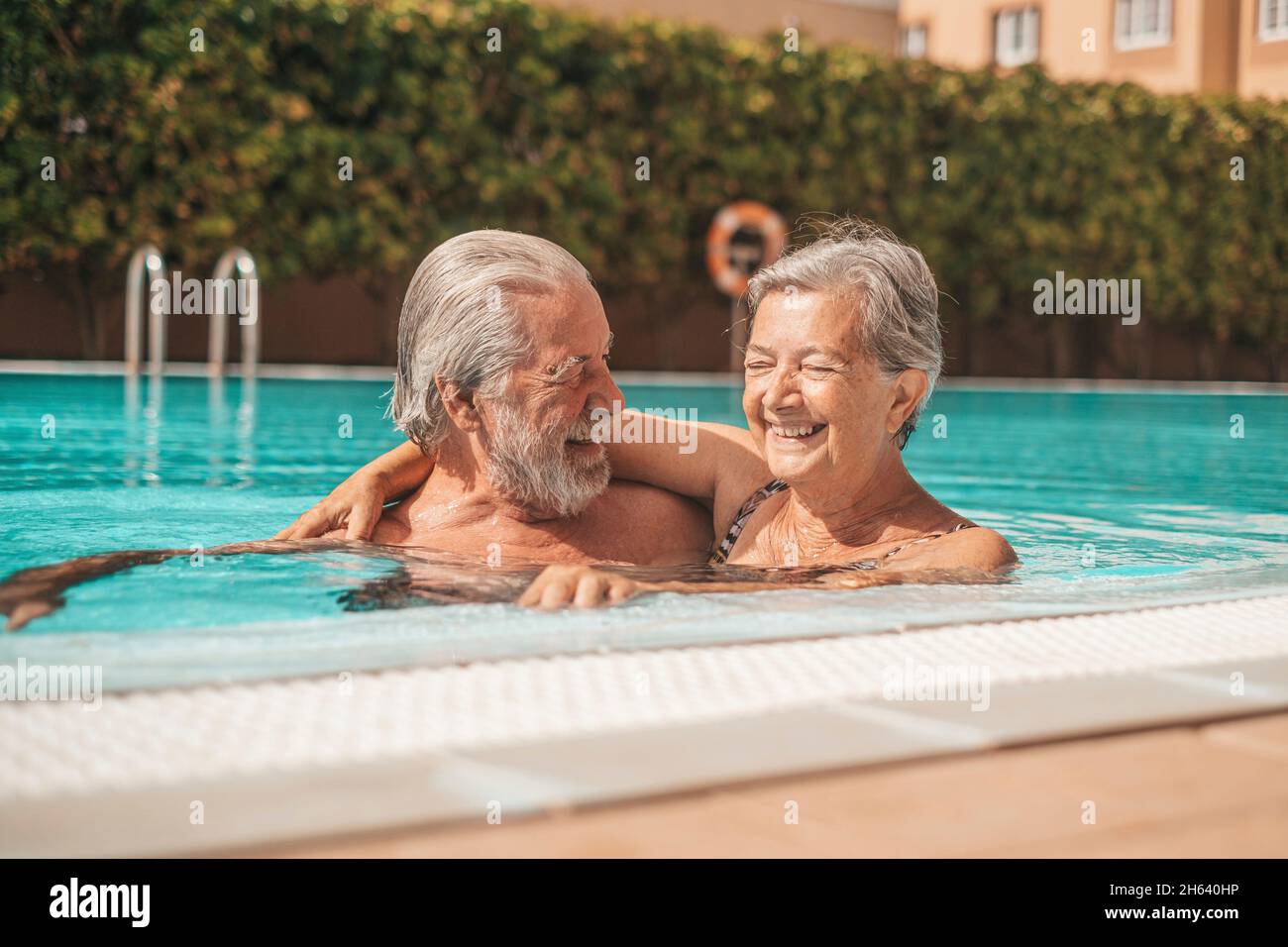 coppia di due anziani felici divertirsi e divertirsi insieme in piscina sorridendo e giocando. persone felici godersi l'estate all'aperto in acqua Foto Stock