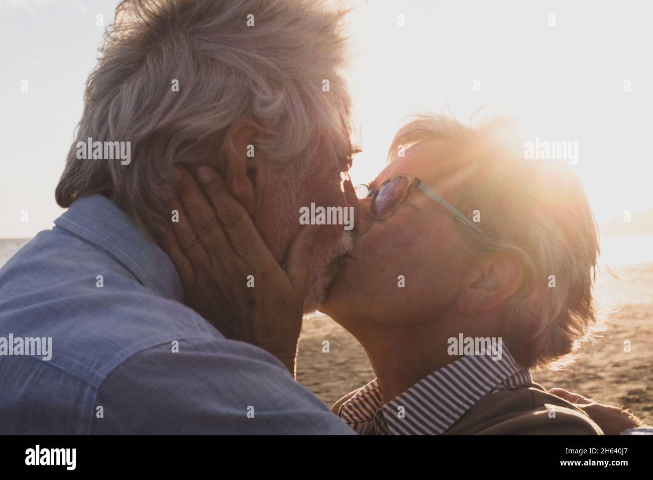 ritratto e primo piano di due felici in amore anziani che ballano sorridendo con il sole del tramonto tra le loro teste Foto Stock