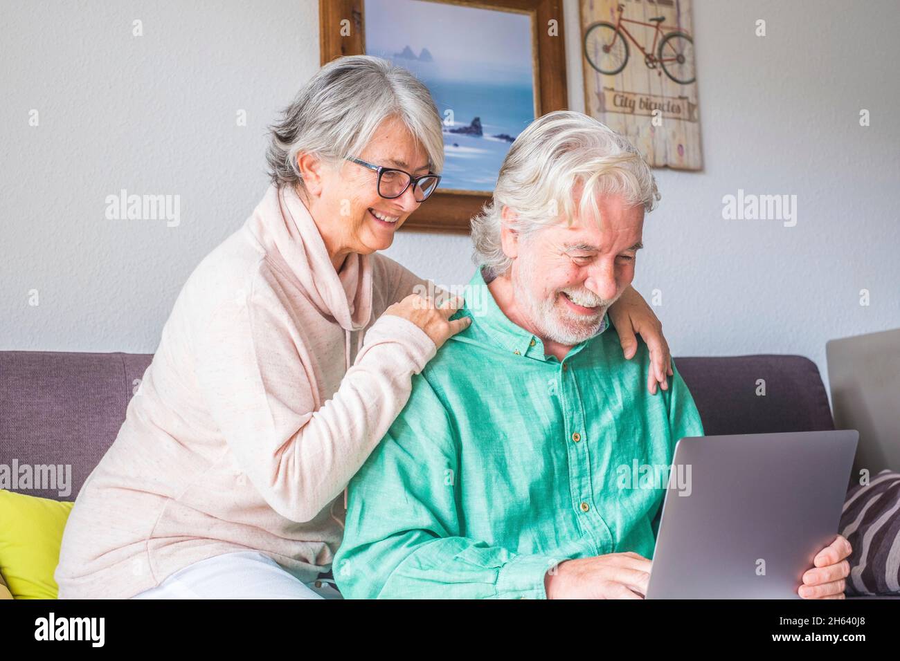 due persone anziane e mature a casa usano il tablet in un divano. i senior usano il notebook divertendosi e divertendosi a guardarlo. concetto di tempo libero e libero Foto Stock