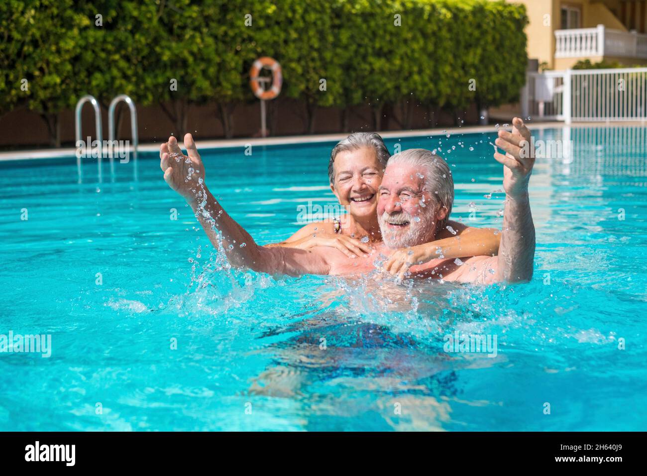 coppia di due anziani felici divertirsi e divertirsi insieme in piscina sorridendo e giocando. persone felici godersi l'estate all'aperto in acqua Foto Stock