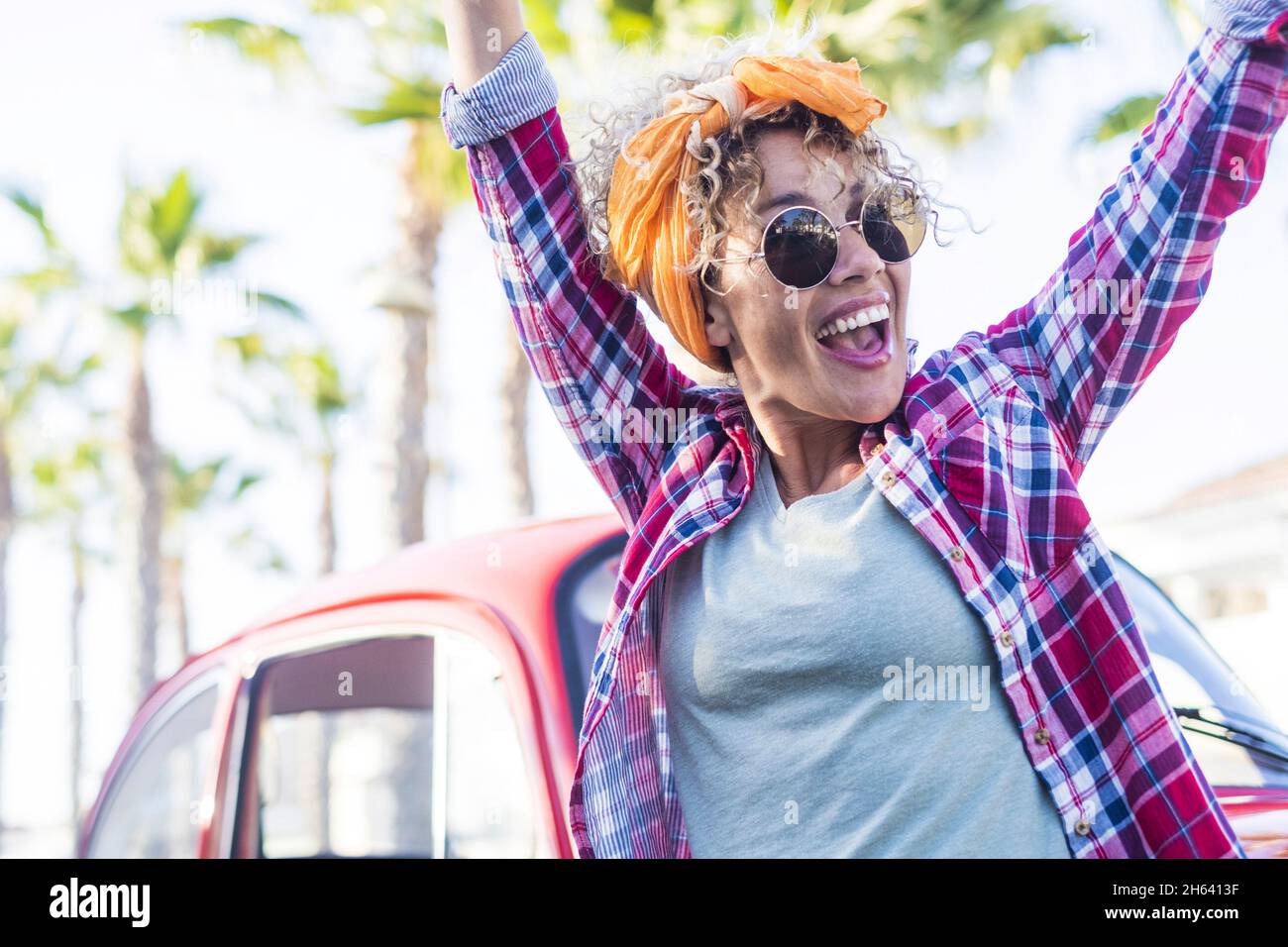 bella donna adulta exult eccitata all'aperto con auto rossa e palme alberi in background - vacanza stile estate viaggio stile di vita con allegro femminile persone - celebrazione tempo una persona Foto Stock