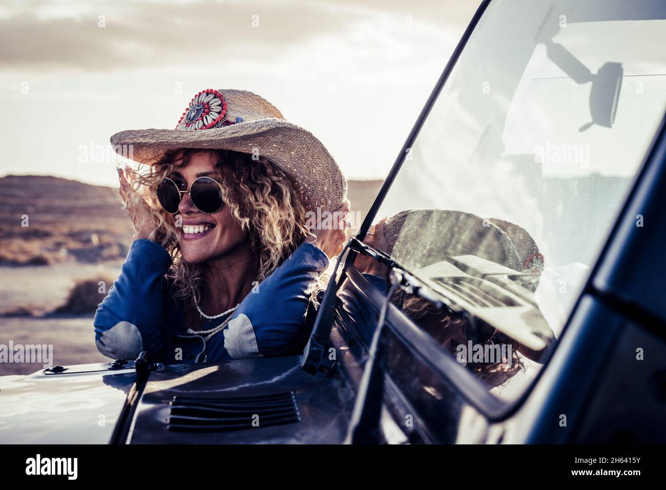 allegro alla moda bella bionda giovane donna adulta sorriso e godere di viaggio in auto in campagna avventura - le persone femminili hanno divertimento durante il viaggio veicolo viaggio all'aperto Foto Stock
