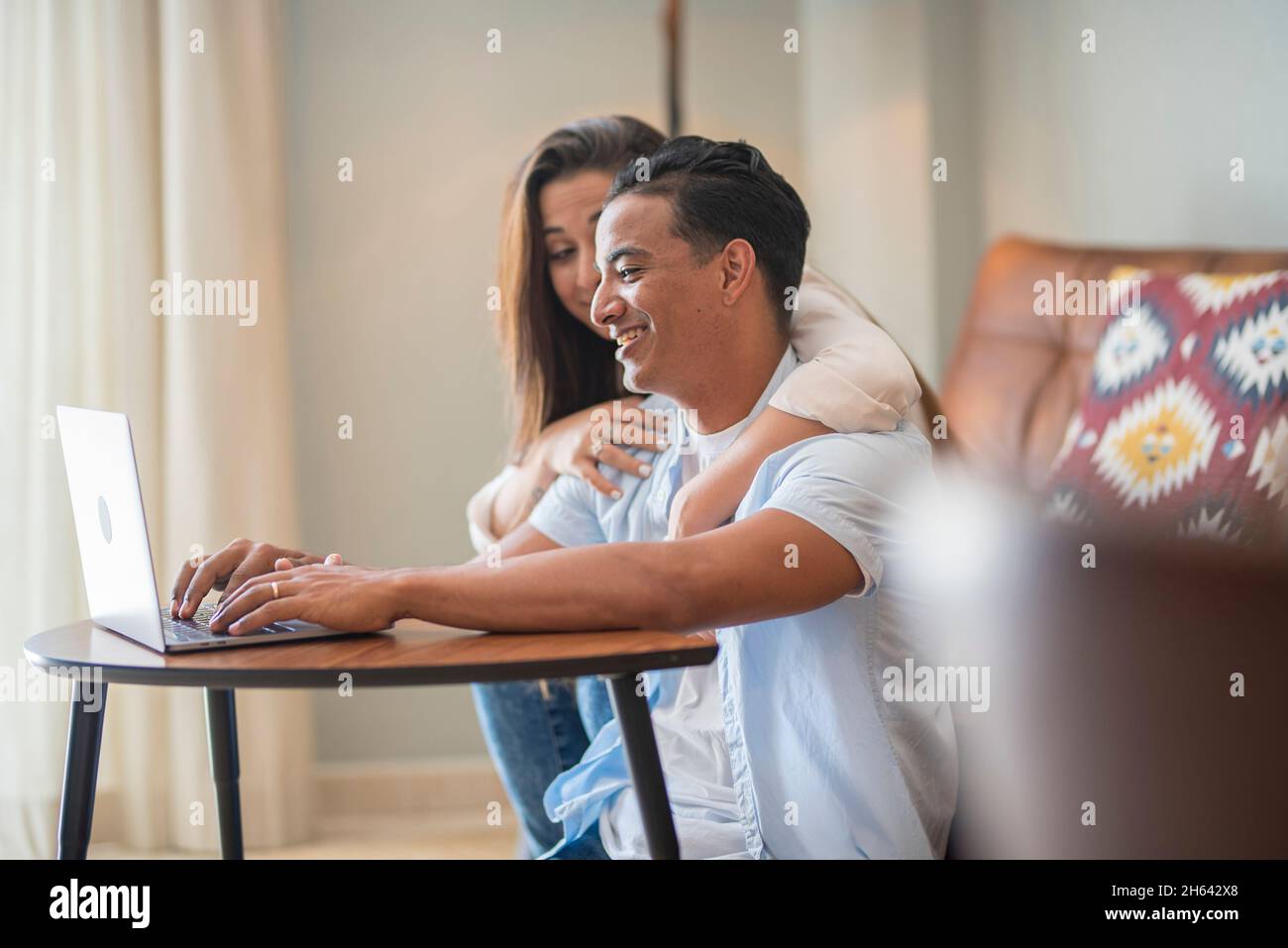 le giovani coppie usano il computer portatile a casa seduti sul pavimento - persone innamorate e in vita insieme con la tecnologia wireless shopping attività online - allegro felice persone indoor Foto Stock