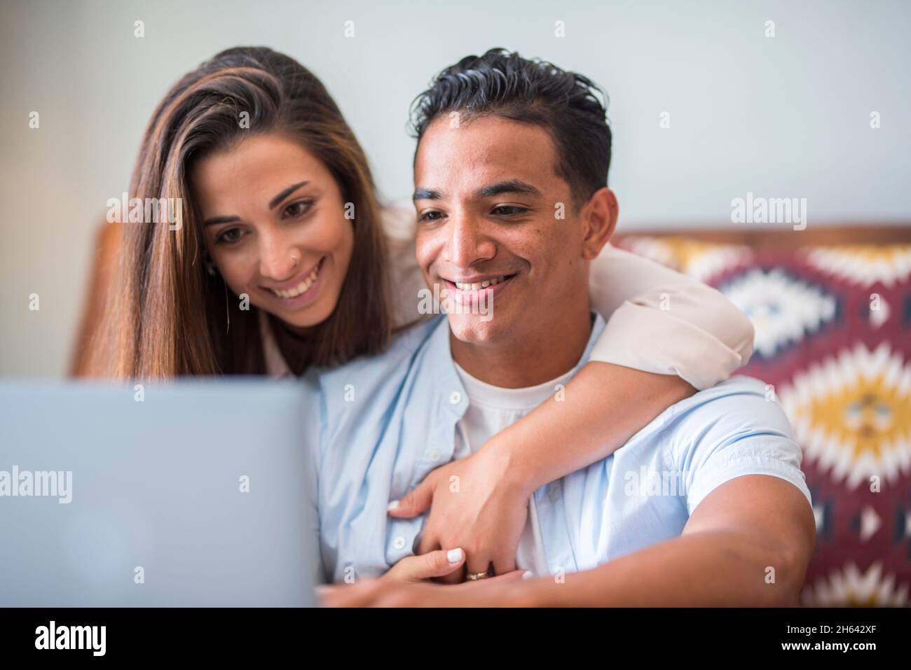 giovane coppia interrazziale che lavora insieme con il laptop. la gente lifestyle a casa insieme usando la connessione internet - uomo e donna godono del computer e del lavoro moderno in linea libero e felice Foto Stock