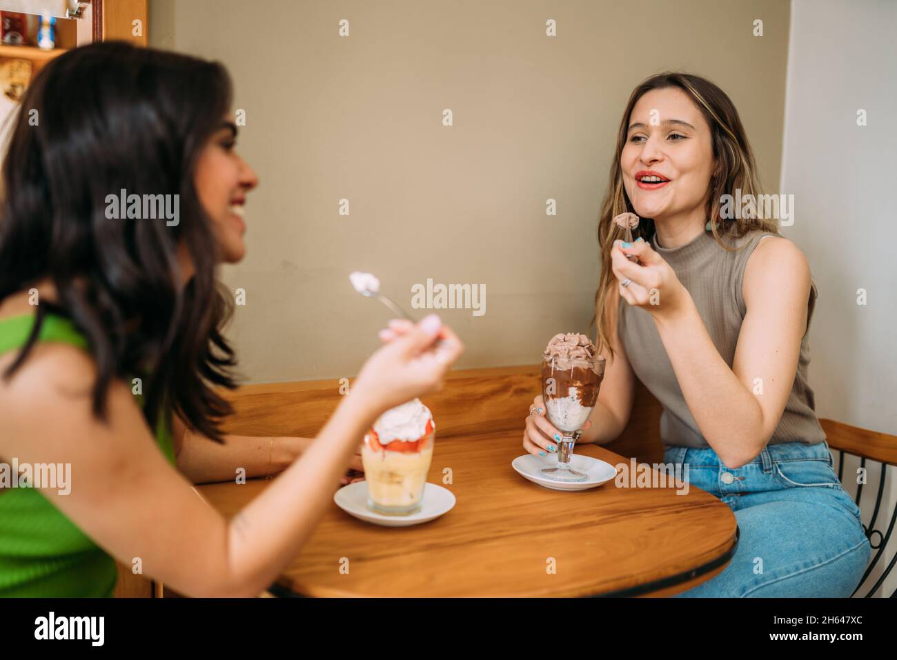 Giovani ragazze latine che siedono in un caffè ascoltando la storia di vita divertente del loro amico Foto Stock