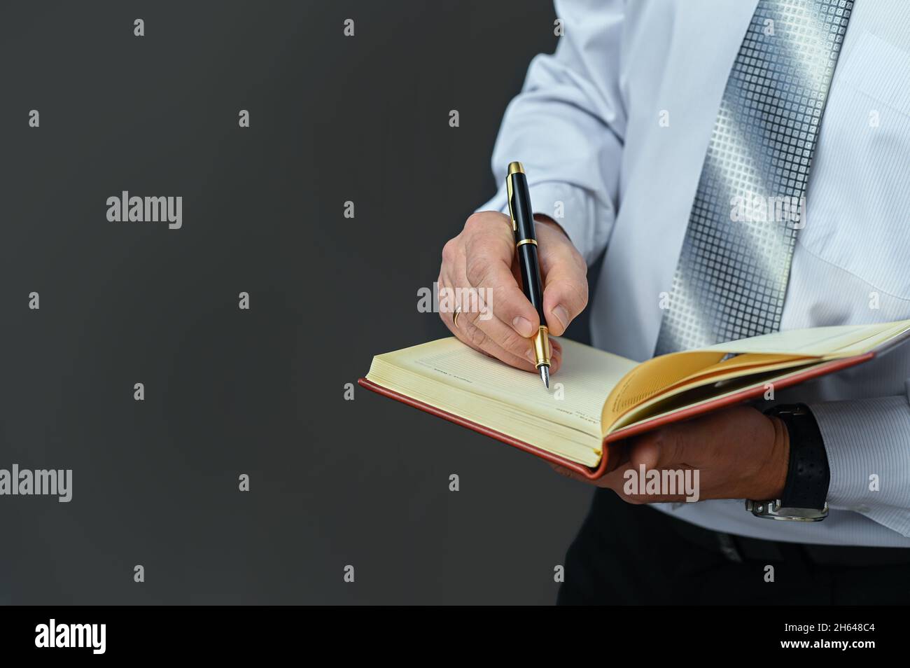 Un uomo d'affari prende appunti in un notebook con una penna stilografica Foto Stock